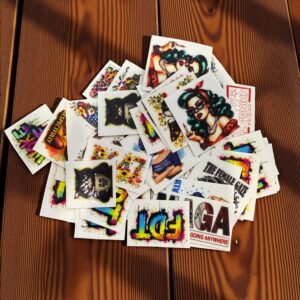 Assorted mini UV DTF transfer designs arranged in a stack on a wooden surface.