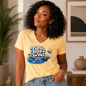 Woman wearing a Too Big to Wig t-shirt featuring an illustrated political parody wave scene.