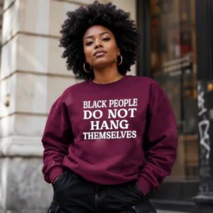 Woman wearing a burgundy Black People Do Not Hang Themselves crewneck sweatshirt